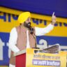 a man standing at a podium with a microphone and a yellow turban